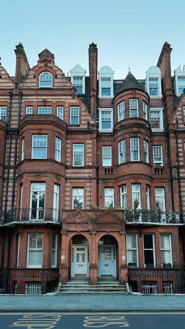 A multi-storey Victorian-style brick building with ornate architectural features, including arched windows, decorative brickwork, and small balconies on the lower floors, situated on King Street in Hammersmith. In front of the building, a street with a parking area is visible, and the entrance features steps leading up to a double door. No moving equipment or personnel are visible in the image, which appears to be taken during daylight with clear skies. This building may be part of a residential or mixed-use property, and it is situated in an urban area suitable for house removals or home relocation services, as represented on the website removalvanhammersmith.co.uk.